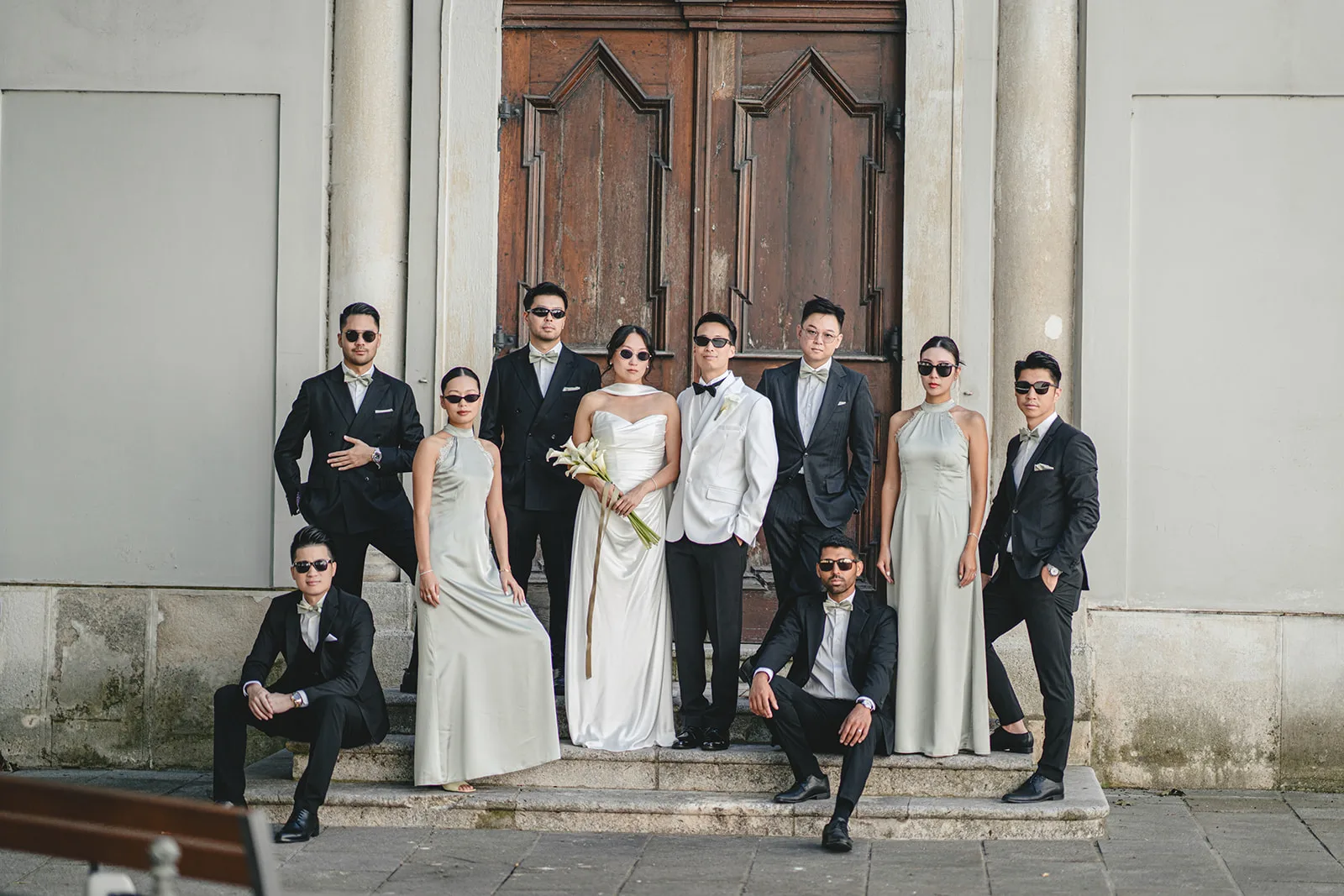 Group photograph of the entire wedding party before a classical backdrop