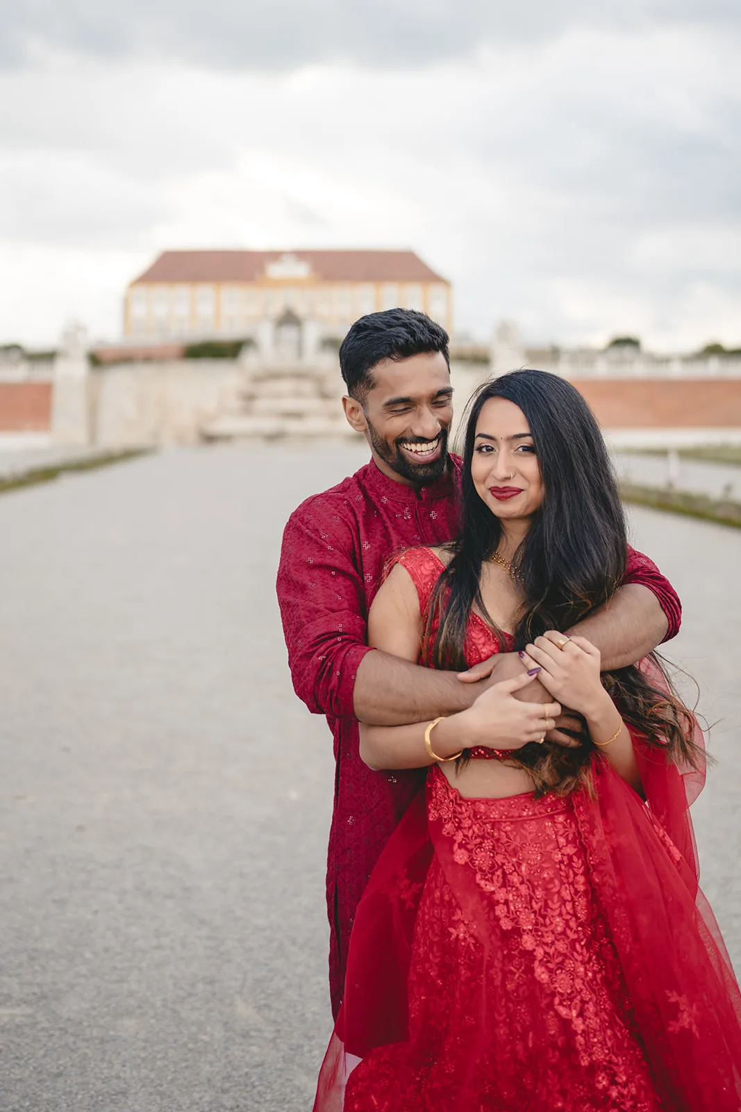 Paar in roter indischer Hochzeitskleidung vor Schloss Hof, Niederösterreich — indische Hochzeit in Europa