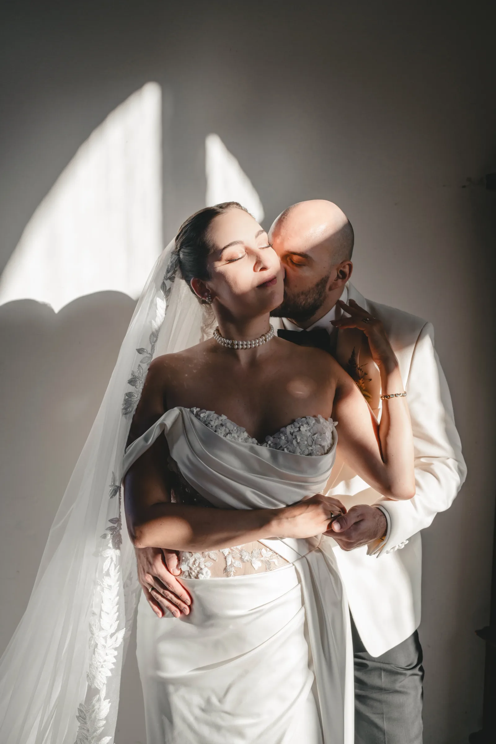 Groom kissing the bride on the cheek in the sunlight — wedding photography in Europe